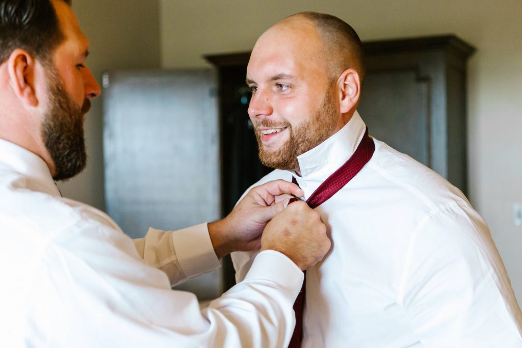 groom accessories groomsman tying his tie Carrie McGuire Photography Temecula Wedding Photography Ponte Inn and Winery 