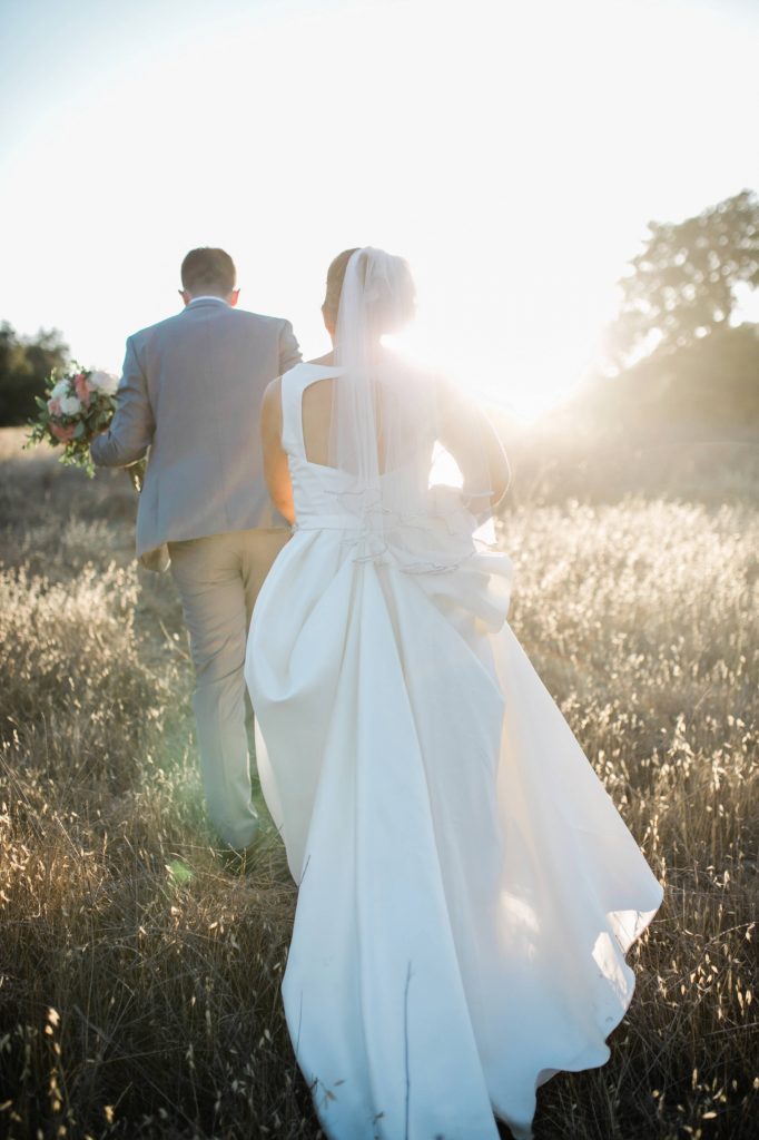married couple walking through the field at forever and always farm at sunset