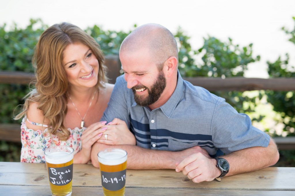 happy couple enjoying a beer and laughing together belching beaver vista California Carrie McGuire Temecula wedding engagement Photography 