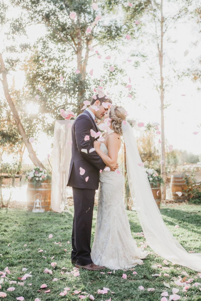 bride and groom kissing under a shower of flower petals Temecula Coachhouse California wedding engagement photography Carrie McGuire photographer California