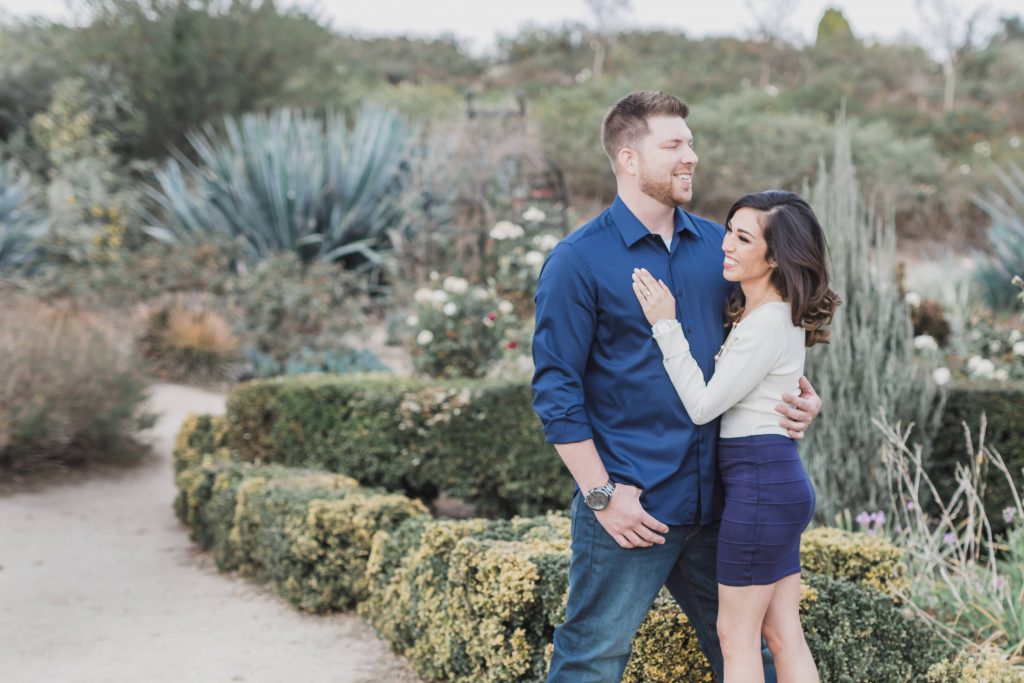 couple holding each other in garden Temecula wedding and engagement photographer session rose heritage gardens California wedding engagement photography Carrie McGuire California