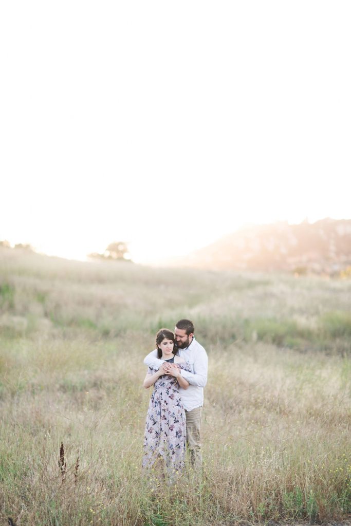 engaged couple embracing at sunset in beautiful field forever and always farm Temecula wedding photography engagement photos Carrie McGuire Photographer