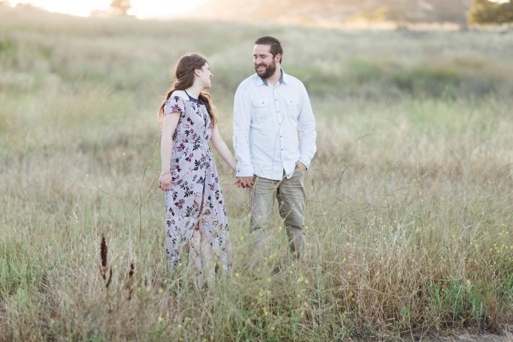engaged couple holding hands at sunset in beautiful field forever and always farm Temecula wedding photography engagement photos Carrie McGuire Photographer