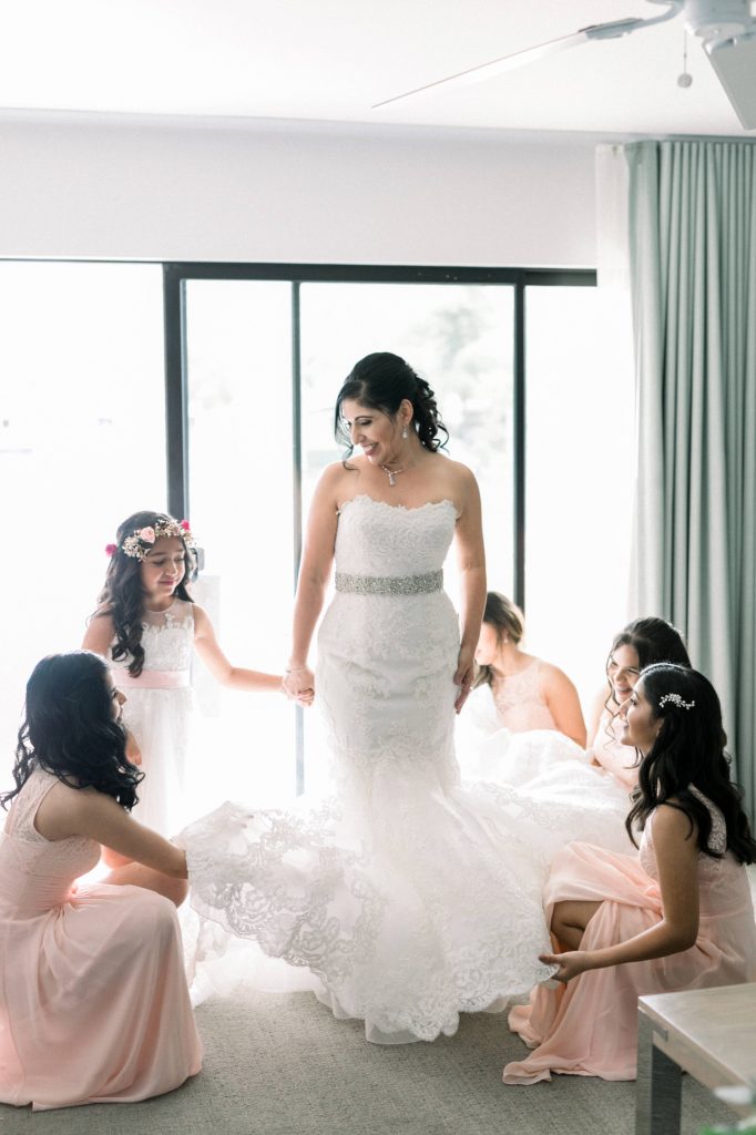 bride and bridesmaids playing with dress while getting ready Lakehouse Resort San Marcos Rachel and Steven Temecula California wedding engagement photography Carrie McGuire photographer California